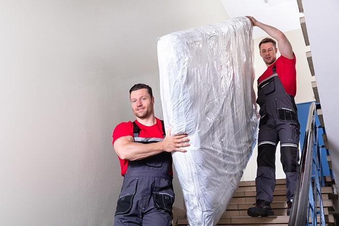 two people carrying a box spring down a staircase in Huber Heights